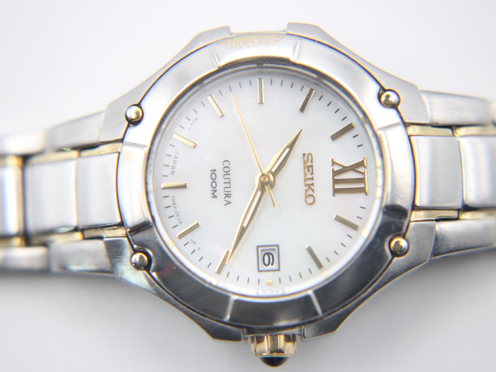 Close-up of the Seiko Coutura white mother of pearl dial, gold-tone indices, and date window.