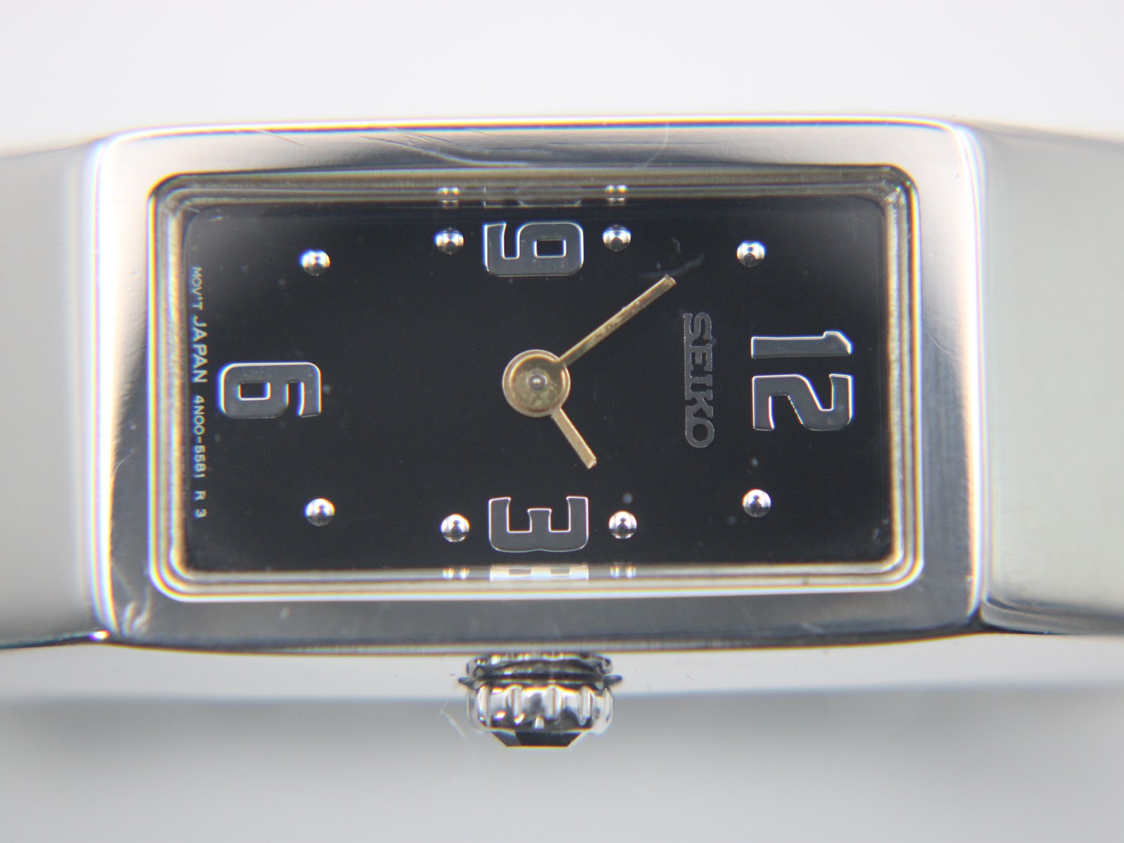 Close-up of the watch dial, showing the applied silver numbers 12, 3, 6, 9, and dot indices on a black background.