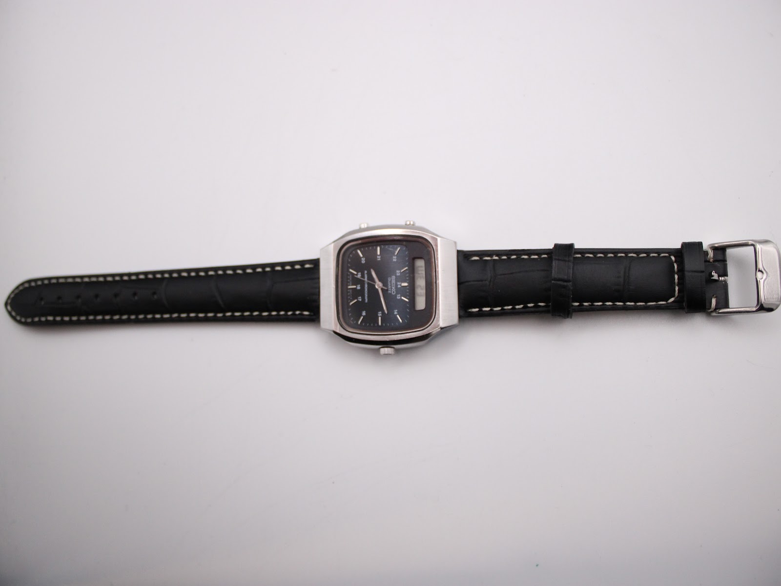 Top-down view of the Seiko H556-5030 watch with black leather strap laid flat.
