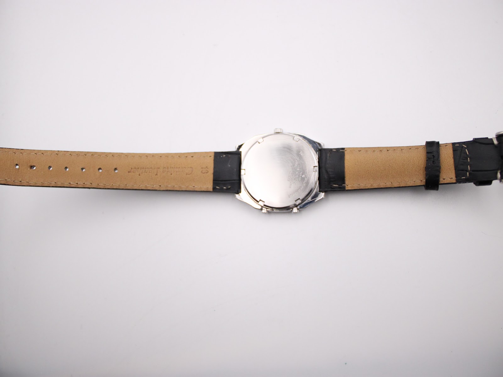 Rear view of the Seiko H556-5030 watch with black leather strap laid flat, showing case back and strap interior.