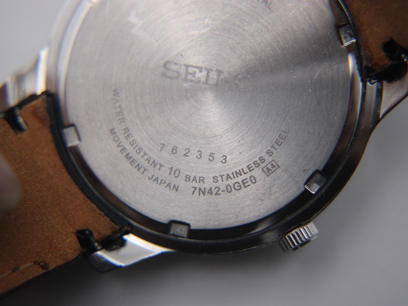 Close-up of the stainless steel case back, showing Seiko branding, serial number (762353), model number (7N42-0GE0), water resistance (10 BAR), and 'stainless steel'.
