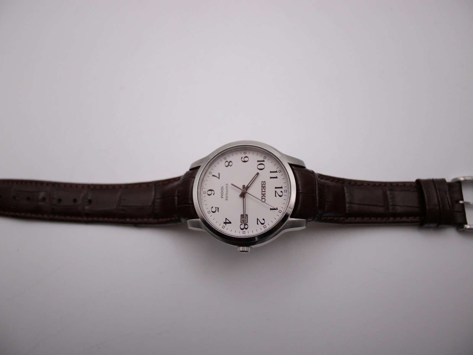 Top-down view of the Seiko watch with its brown leather strap laid flat, showcasing the dial and strap length.