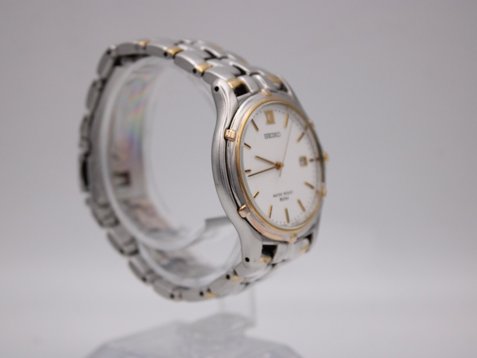 Angled right side view of the Seiko watch, highlighting the gold-tone crown and integrated bracelet design.