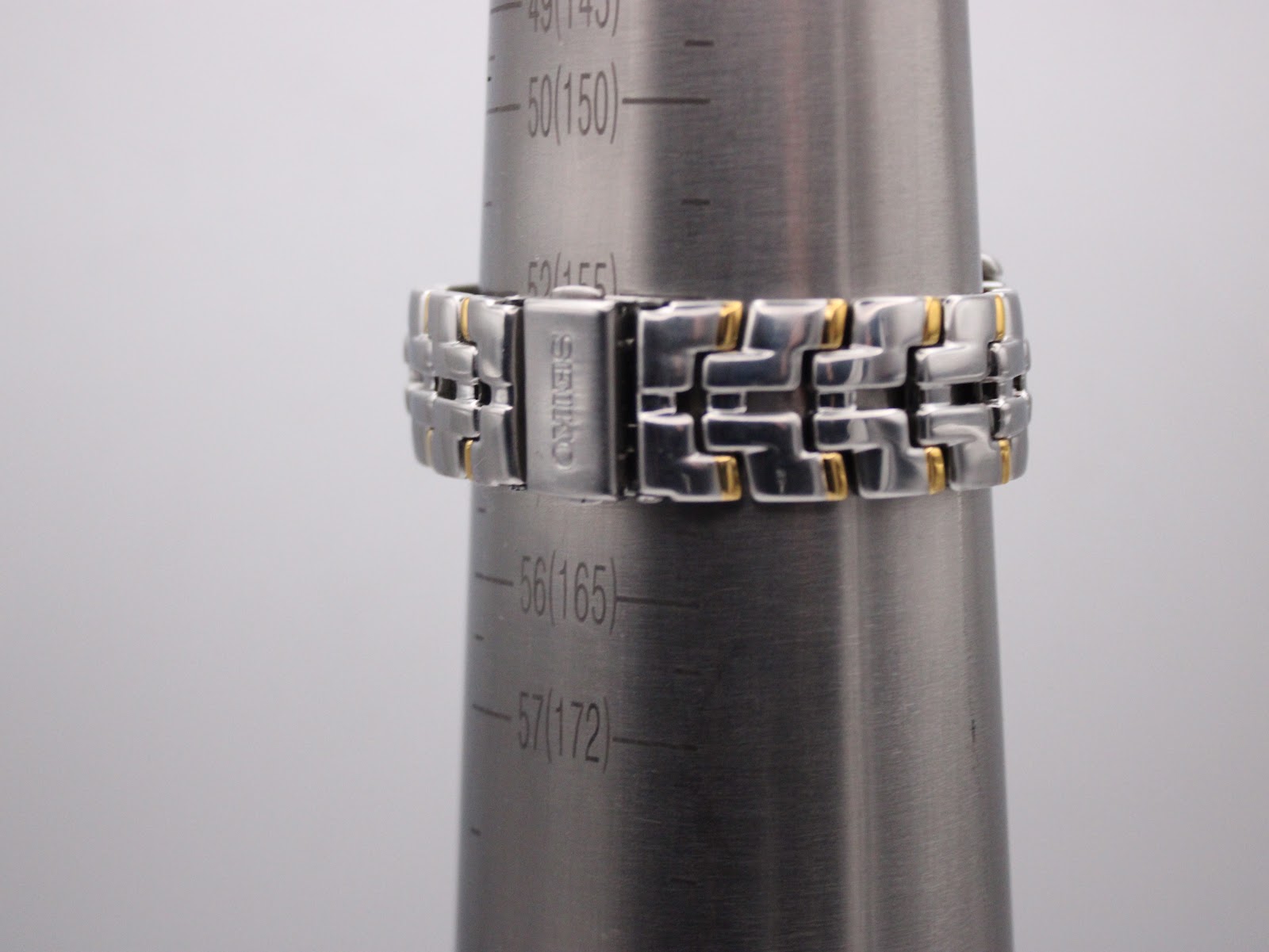 The two-tone bracelet on a wrist sizing gauge, showing a circumference of 165mm (16.5cm), with a signed Seiko clasp.