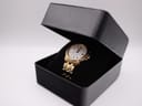 The gold-tone Seiko watch presented in an open black watch box, sitting on a soft black cushion.