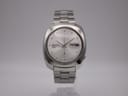 Front view of Seiko 6119-7080 automatic watch with silver sunburst dial and day-date display on integrated stainless steel bracelet.