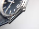 Detail shot of the polished stainless steel case lugs and the textured navy blue leather strap.