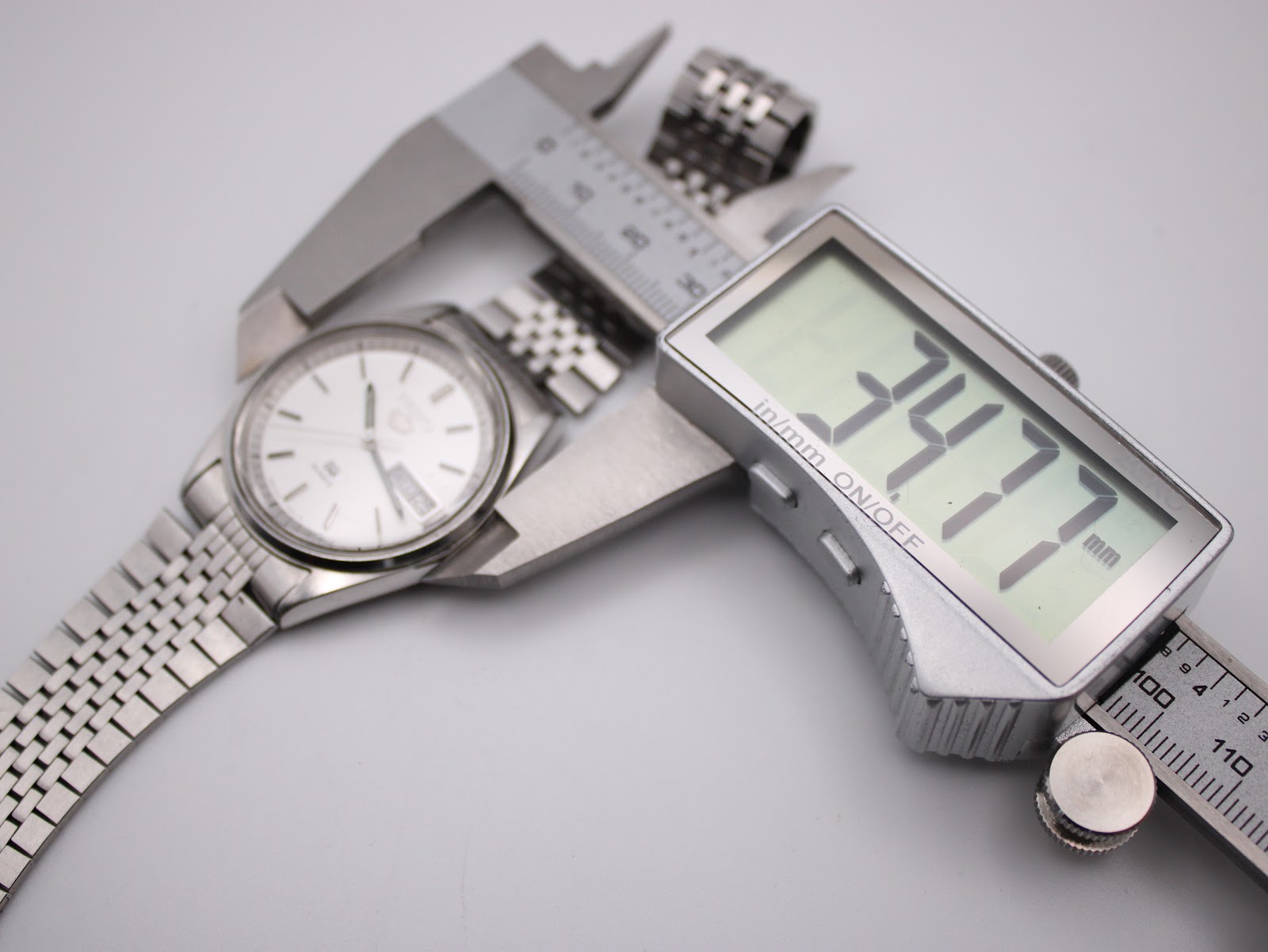 Digital caliper measuring the Seiko 8223-8080 watch case, showing an exact diameter of 34.77mm.