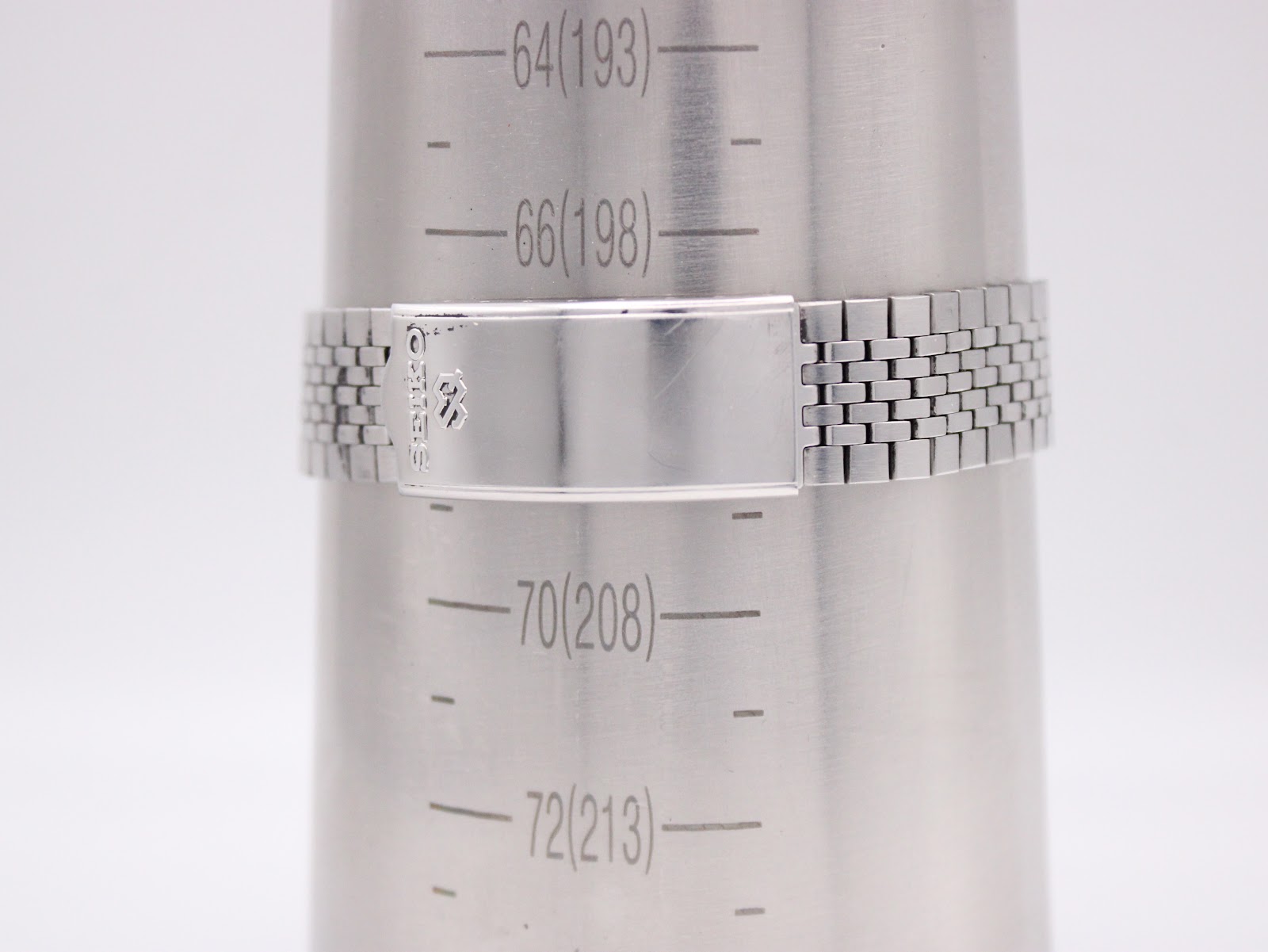Seiko integrated stainless steel bracelet with signed fold-over clasp on a wrist sizing gauge, indicating a wrist circumference of 19.8cm.