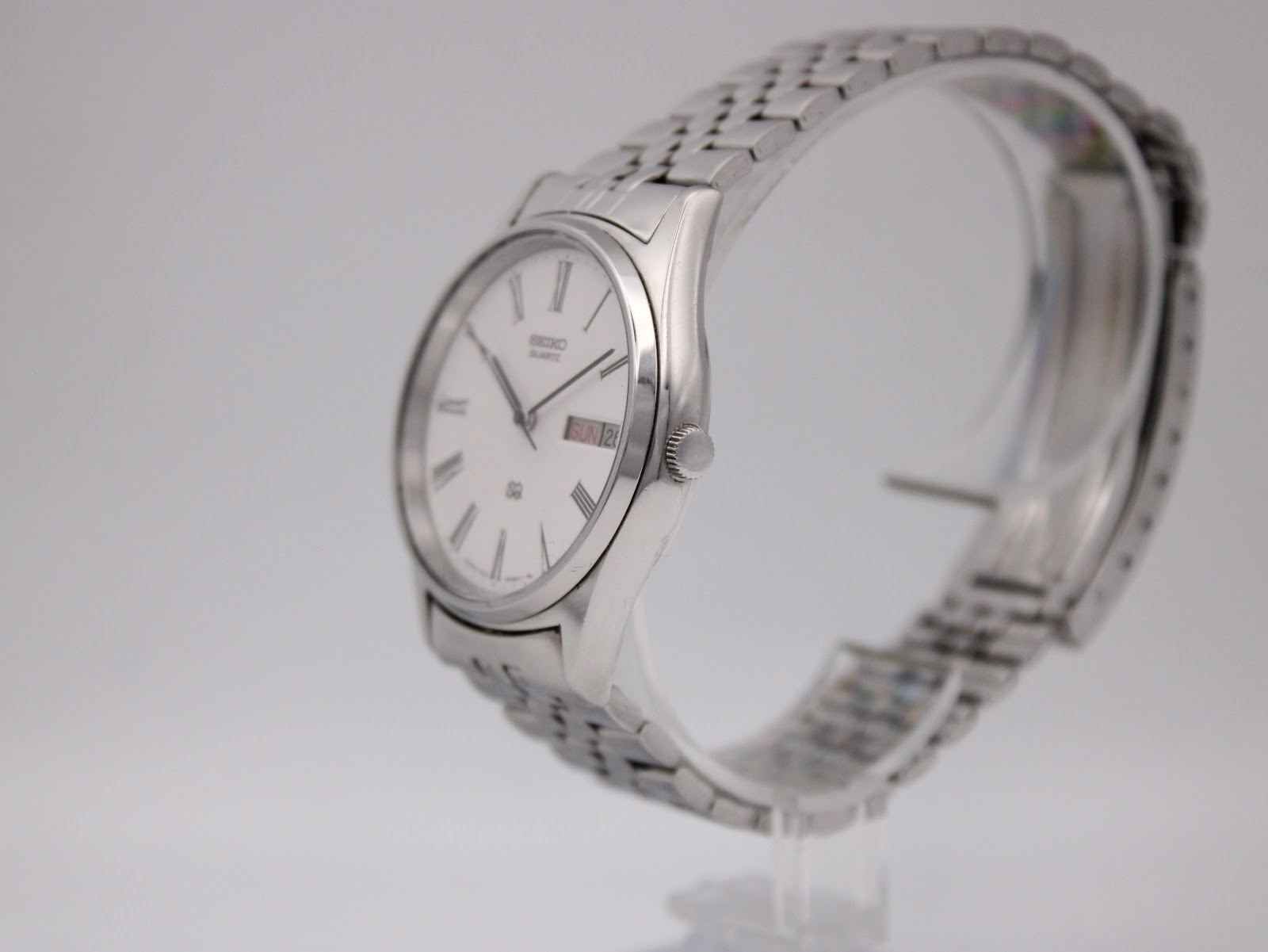 Angled side profile of the Seiko quartz dress watch, highlighting the slim round stainless steel case and polished bezel