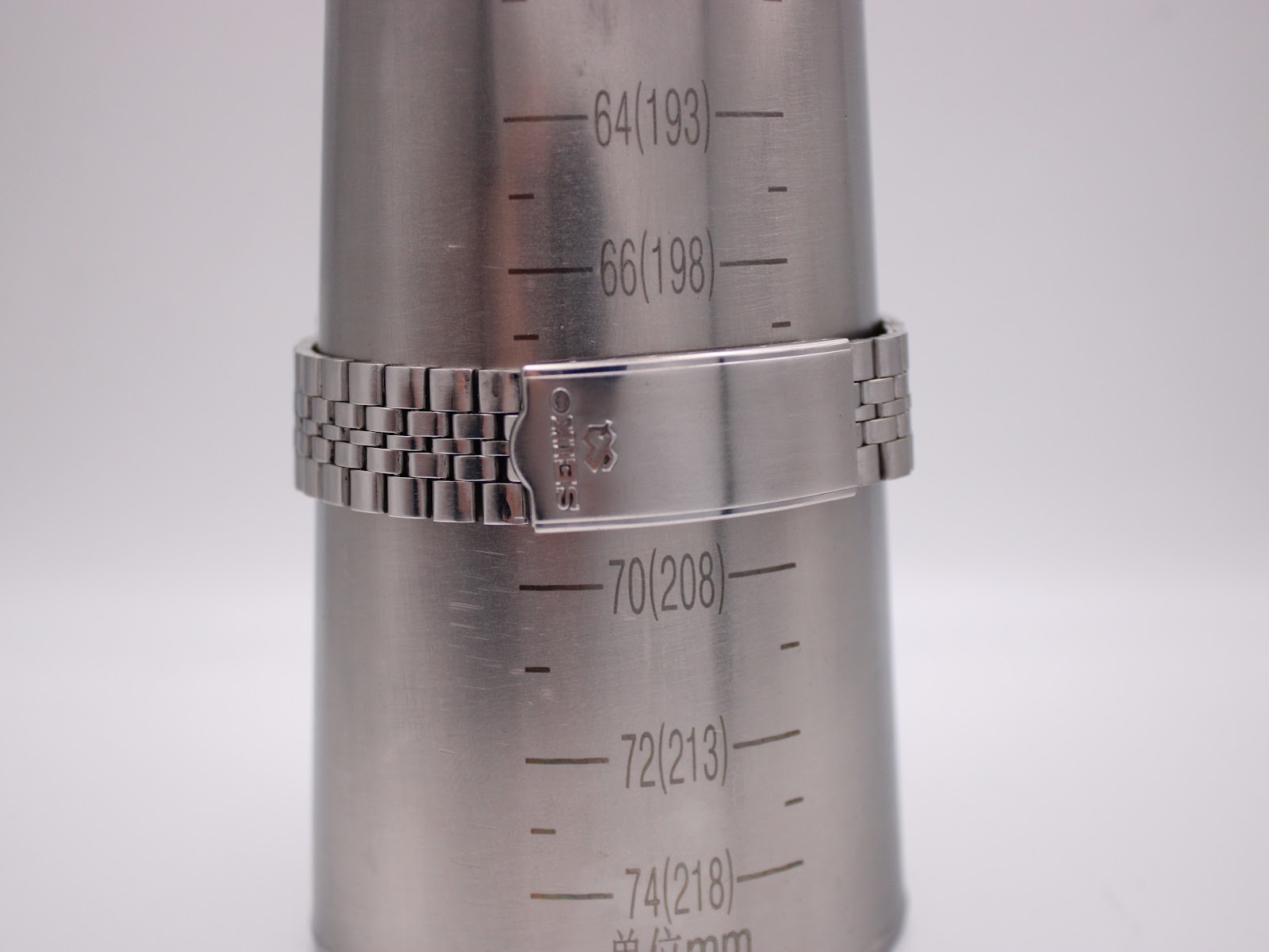 Seiko stainless steel bracelet on a wrist sizing gauge, indicating a maximum wrist circumference of 203mm or 20.3cm