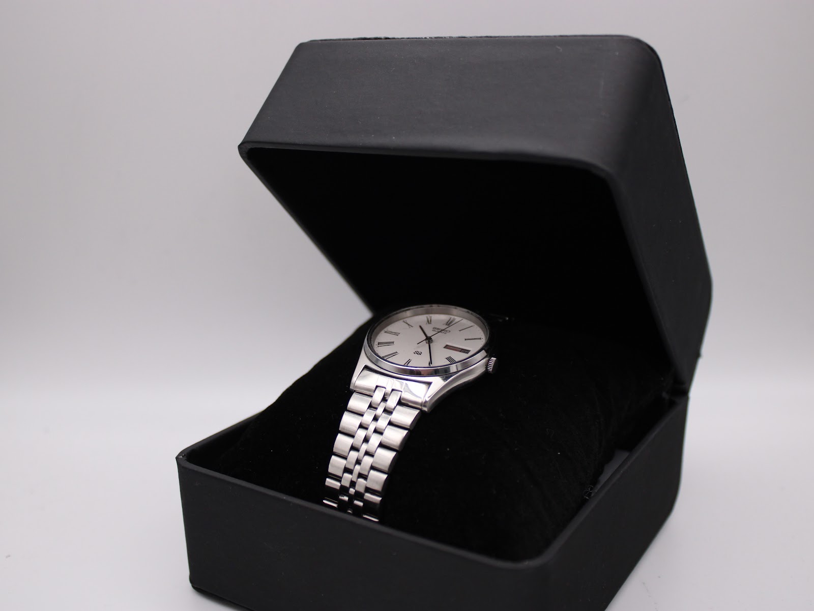 The Seiko 7123-8340 watch resting on a black velvet cushion inside a generic presentation box