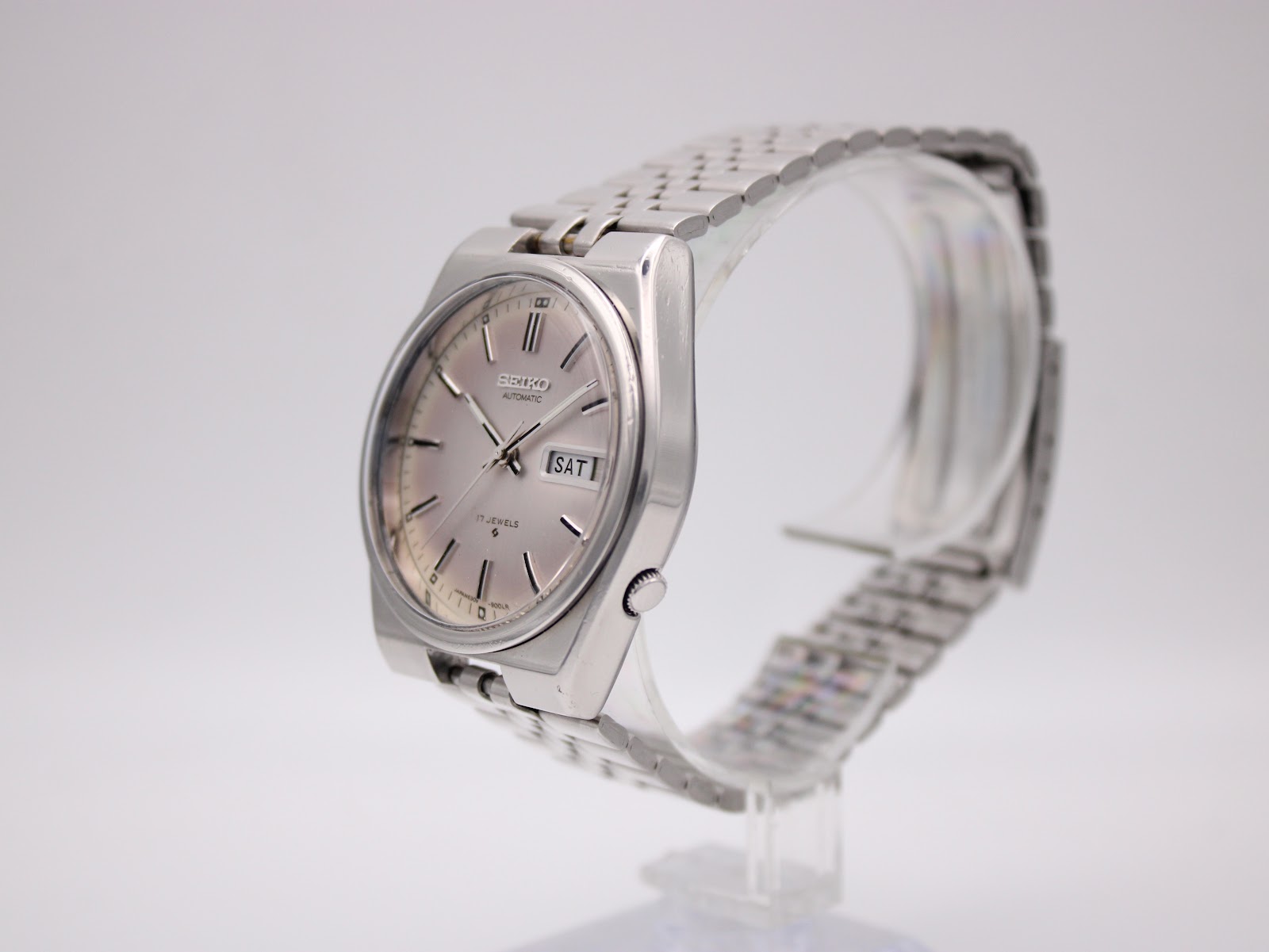 Angled right side view of the vintage SEIKO watch on a clear display stand, highlighting the angular case profile.