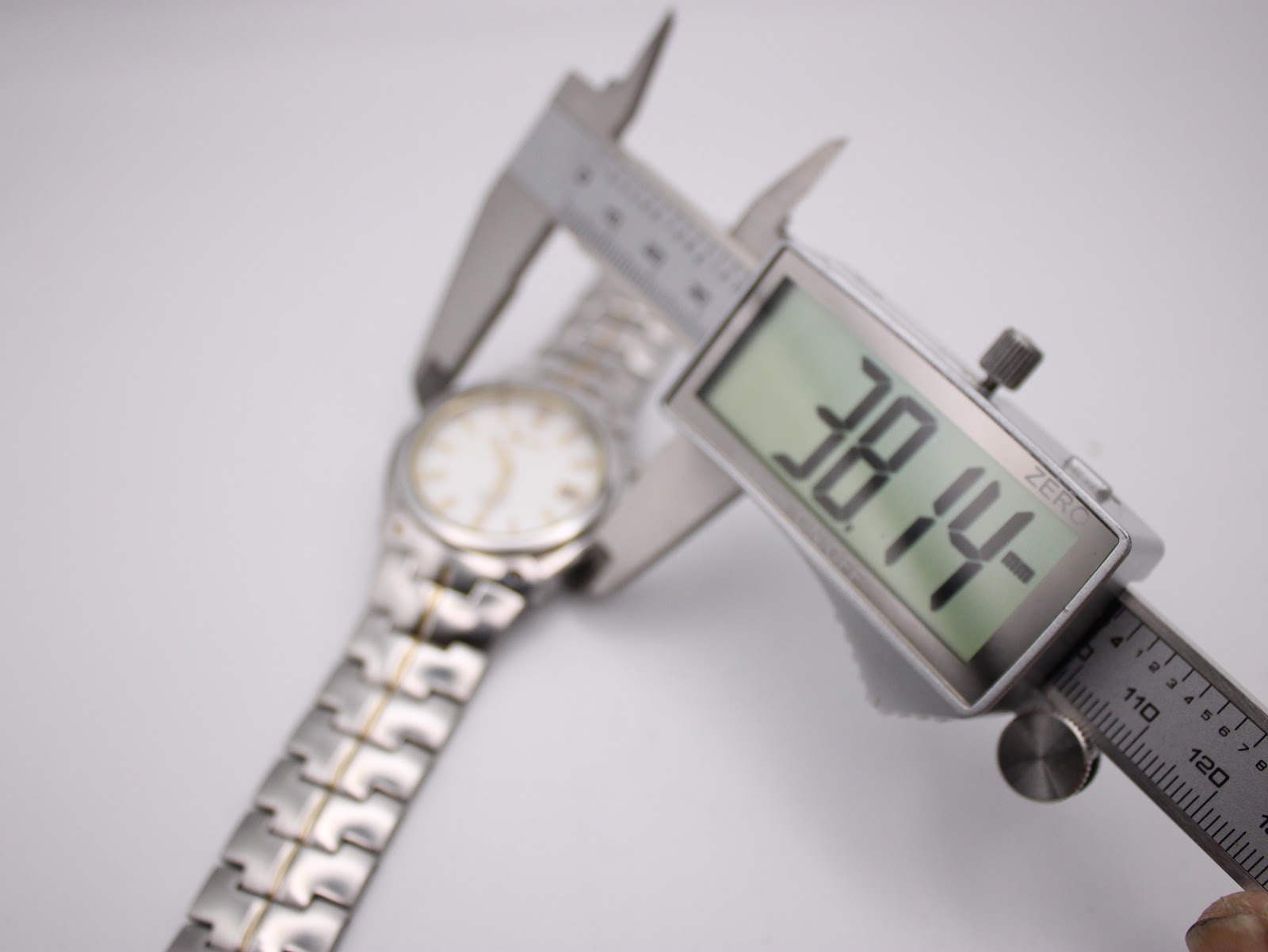 Digital caliper measuring the case diameter of the Seiko watch, displaying a precise measurement of 38.14mm.