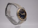 Angled view of the Seiko V743-9020 watch on a display stand, highlighting the two-tone integrated bracelet and case profile.