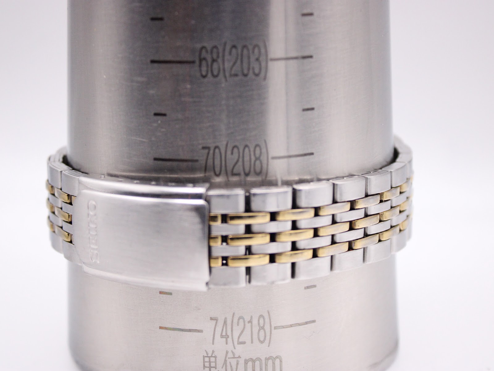 Close-up of the two-tone integrated bracelet with a signed Seiko deployment clasp, measuring 208mm / 20.8cm on a wrist sizing gauge.