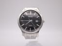 Front view of the Seiko 6N42-00F0 watch with a black dial and date window on a display stand.