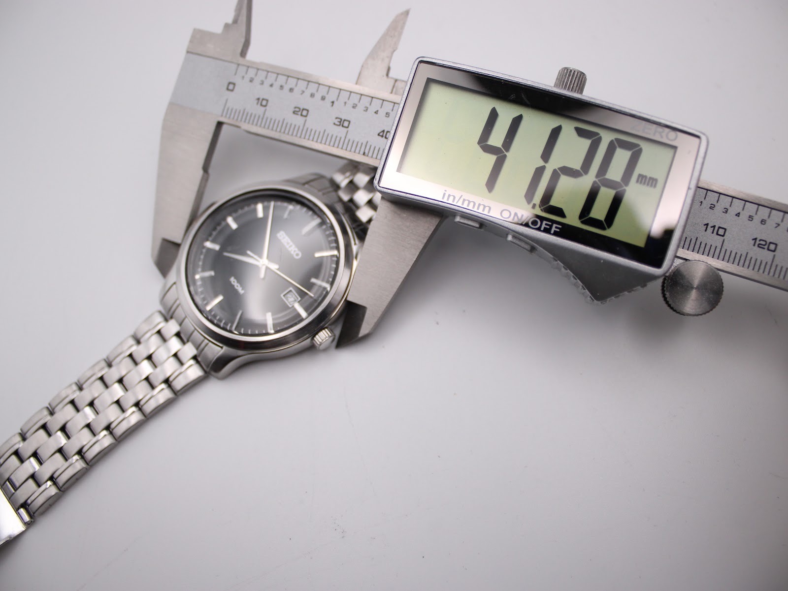 Digital caliper measuring the Seiko watch case diameter, displaying 41.28mm.