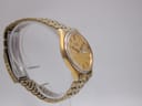 Another side profile of the Seiko watch on a clear stand, angled to show the full gold-tone integrated bracelet.