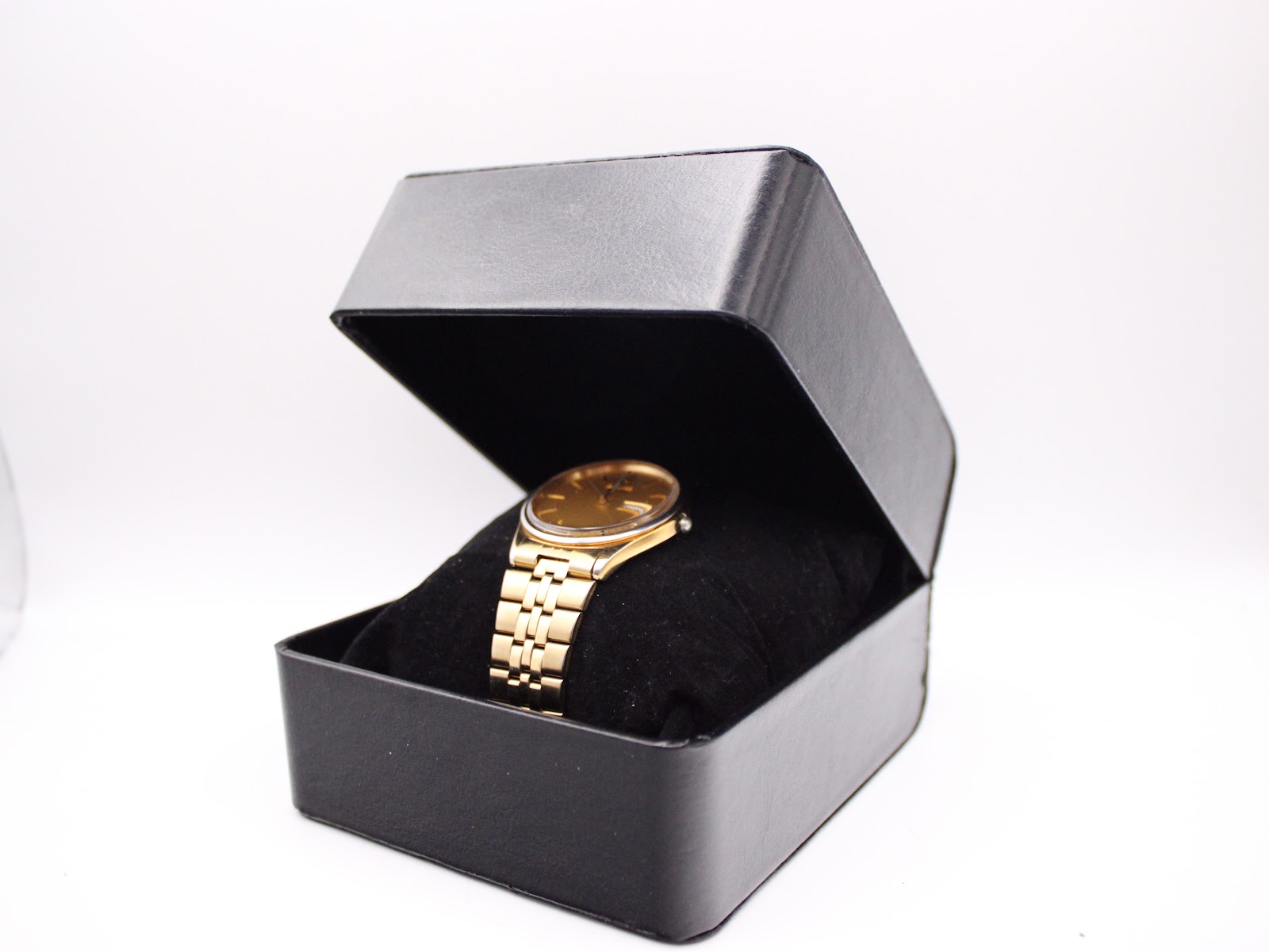 The Seiko gold-tone watch presented inside an open black rectangular watch box with a velvet cushion.