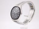 Angled side view of the Seiko watch on a clear stand, showcasing its tonneau-shaped case and integrated steel bracelet.
