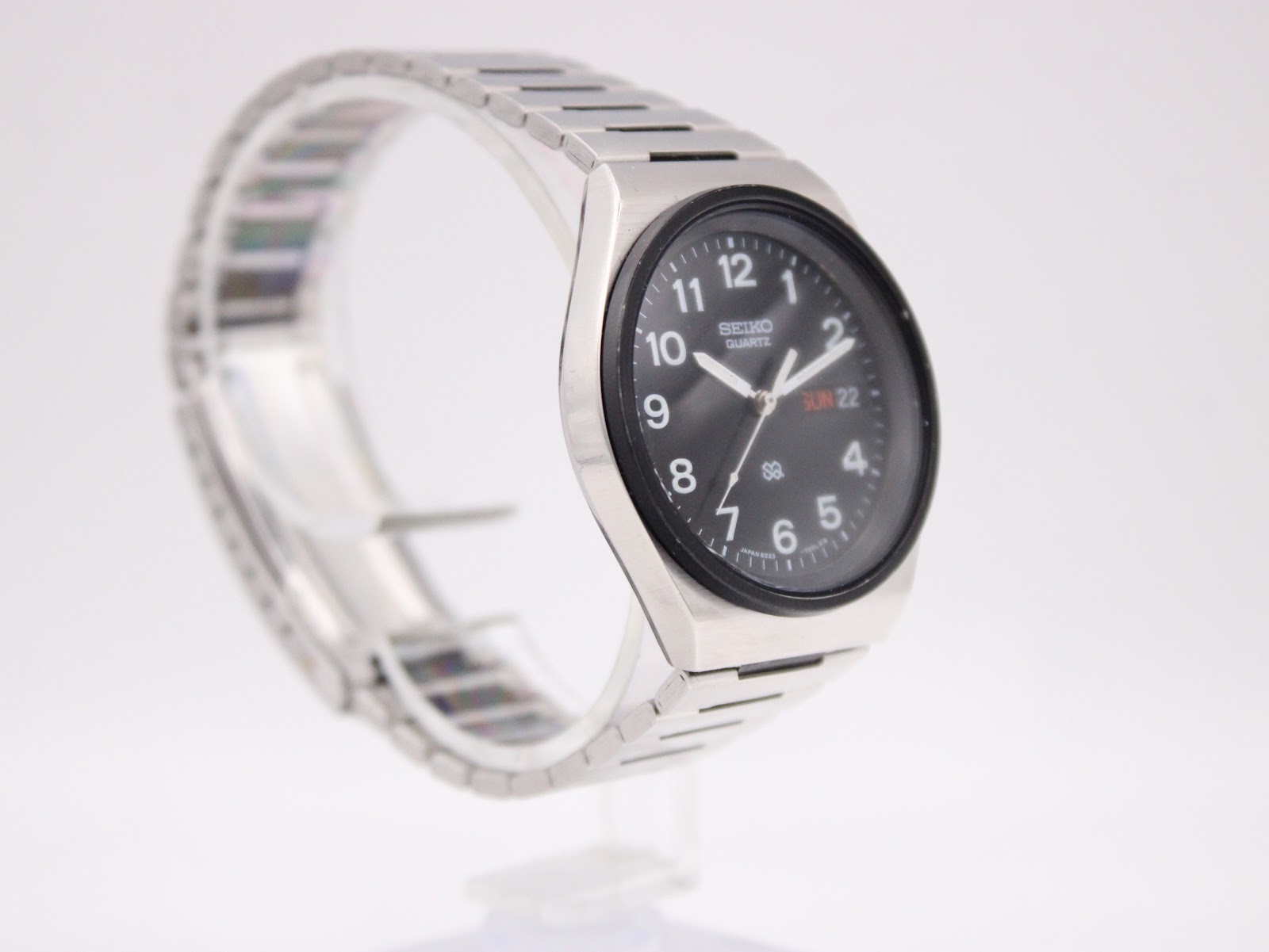 Close-up three-quarter view of the Seiko 8223-704B on a stand, highlighting the brushed finish of the case and bracelet.