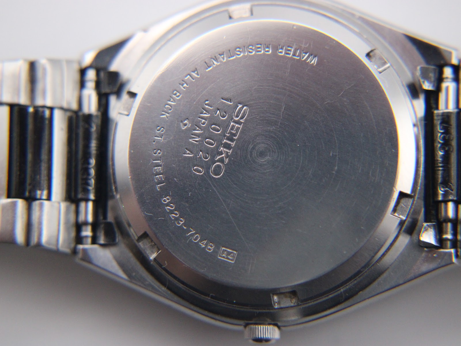 Detailed close-up of the stainless steel case back, showing 'SEIKO', model 8223-704B, serial number 120020, and 'WATER RESISTANT'.