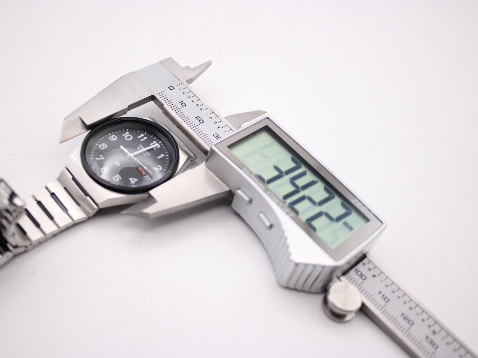 Digital caliper measuring the case diameter of the Seiko watch, displaying a precise measurement of 34.22mm.