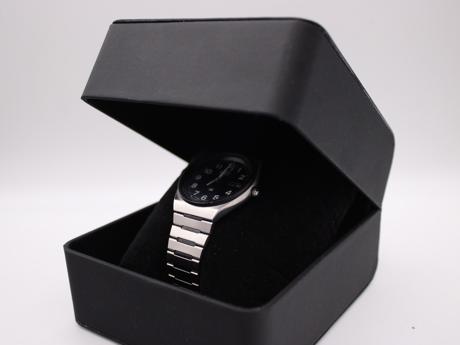 The vintage Seiko watch positioned on a cushion inside an open black presentation box, viewed from an angle.