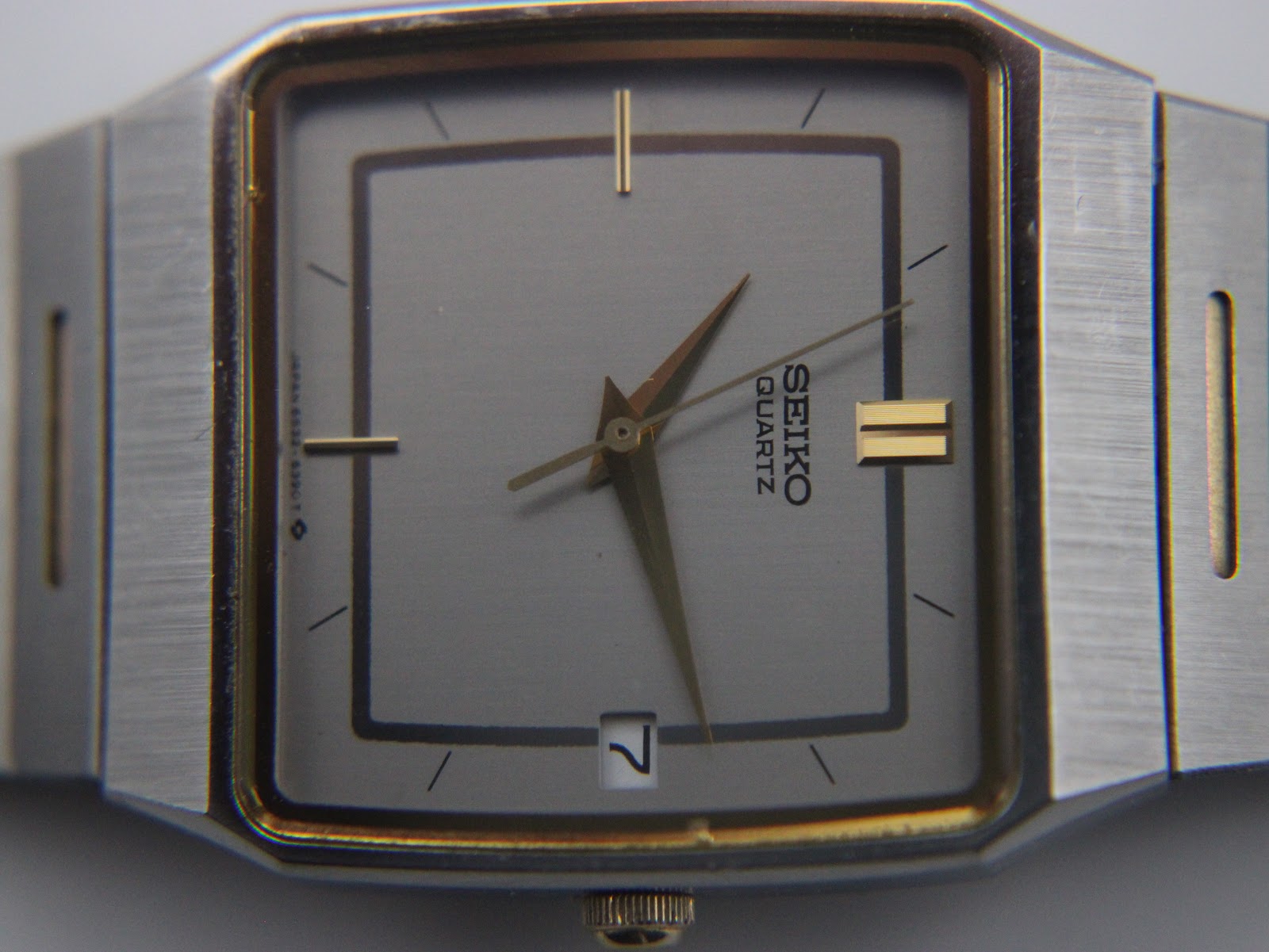 Detailed close-up of the grey dial with gold-tone stick indices, hands, and date window at 3 o'clock.