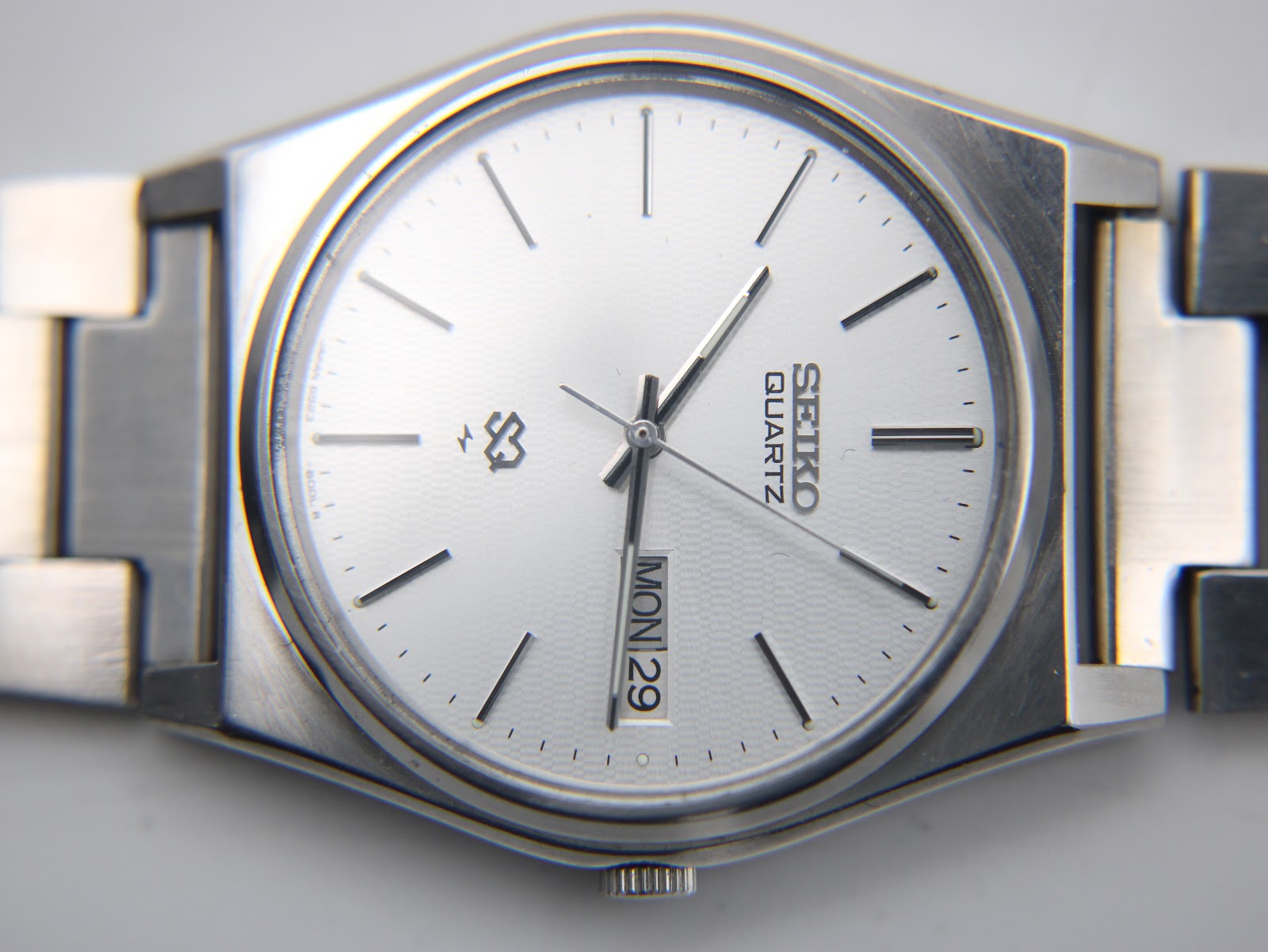 Detailed close-up of the Seiko 6923-8000's silver sunburst dial with day-date display and 'SEIKO QUARTZ' text at 12 o'clock.