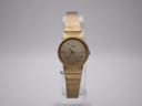 Front face of the Seiko 16-0229 ladies gold tone watch with mesh bracelet, on a clear display stand.