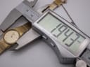 The Seiko watch being measured by a digital caliper, displaying a precise case diameter of 19.43mm.