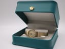 The elegant gold-tone Seiko watch presented inside a teal coloured jewellery box with a distinctive gold crown emblem.
