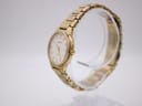 Angled side view of the gold tone Seiko watch on a clear stand, highlighting the case profile and crown.