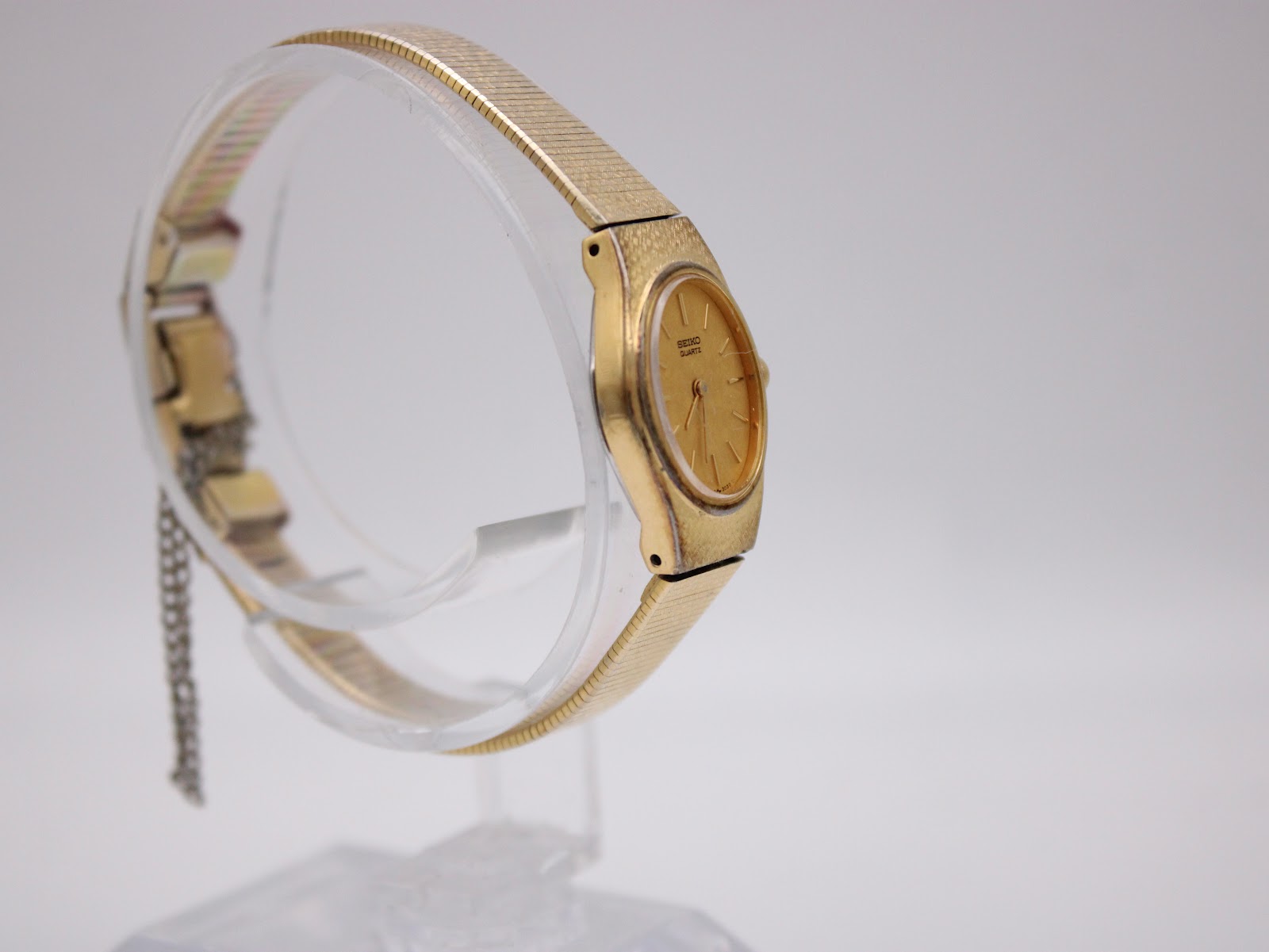 Three-quarter view of the gold Seiko watch on a display stand, showcasing the integrated mesh bracelet.