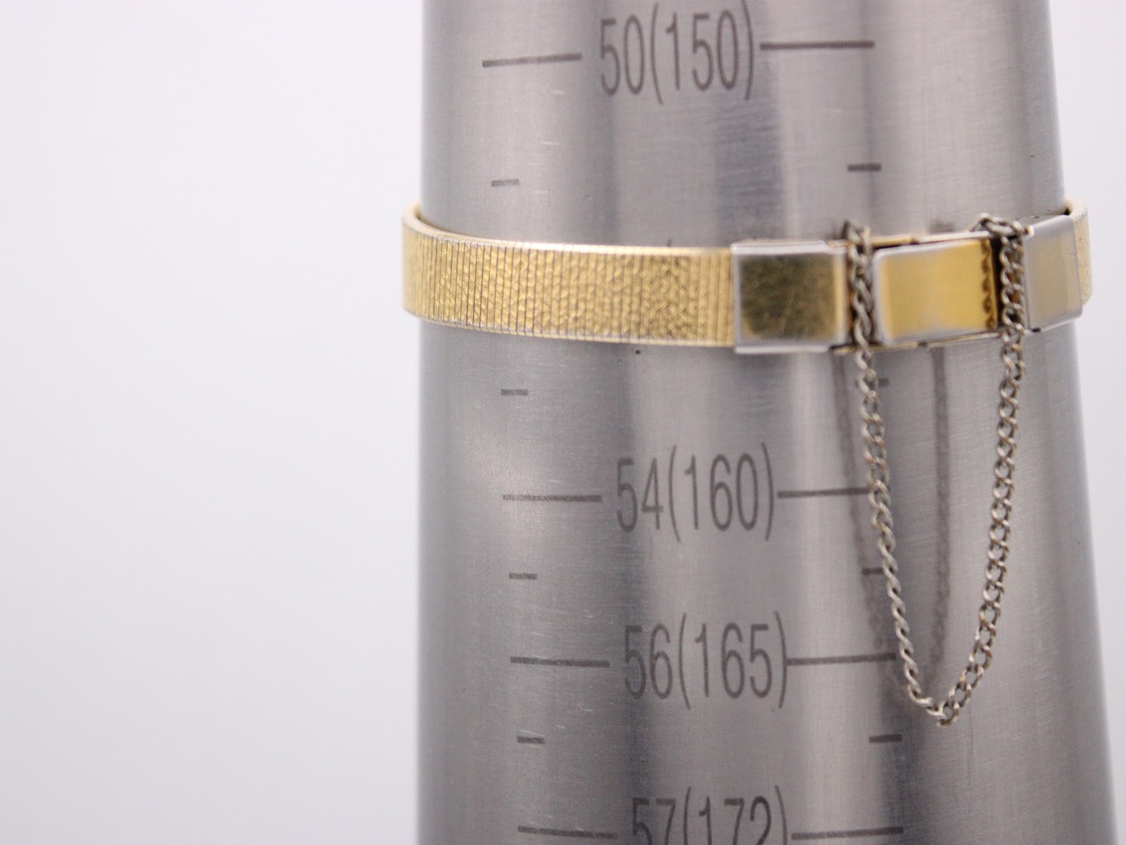 The gold mesh bracelet of the Seiko watch wrapped around a wrist sizing gauge, indicating a size of approximately 15.5cm.