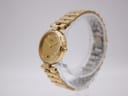 Side profile of the gold Seiko watch showing the rounded case and integrated link bracelet on a clear stand.