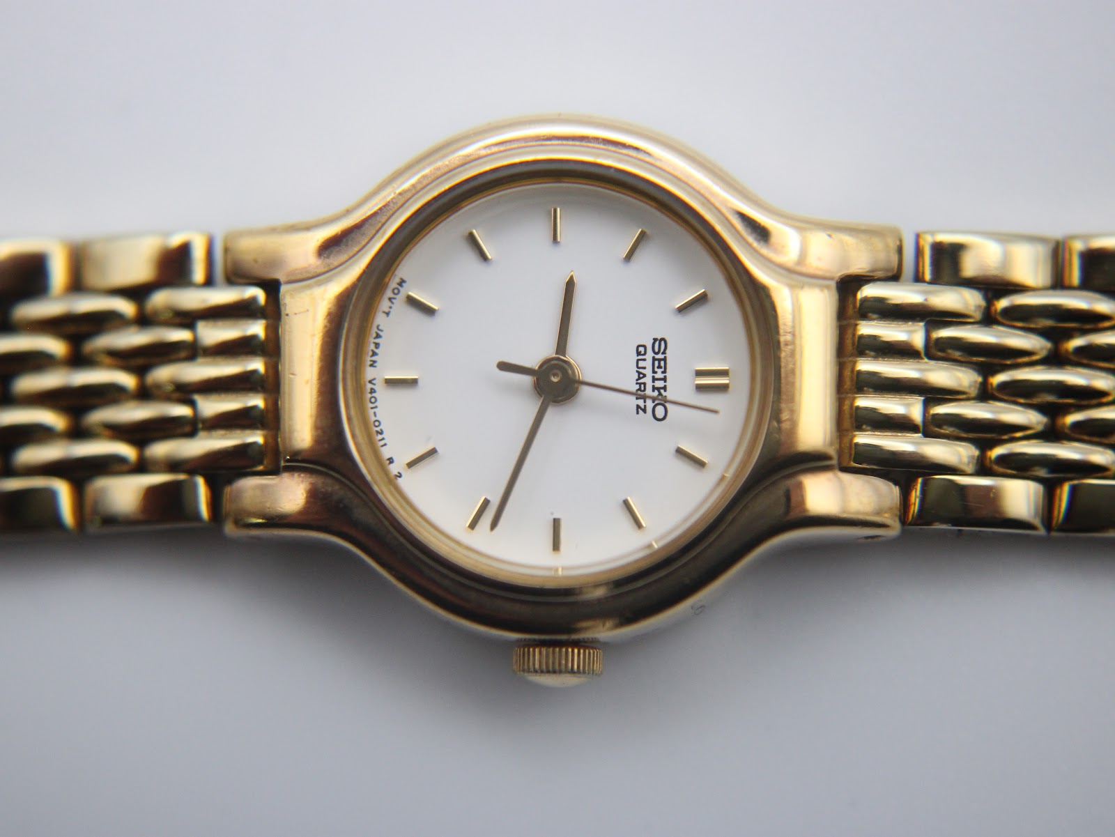 Gold-tone integrated steel bracelet of the Seiko watch, shown on a wrist sizing tool.