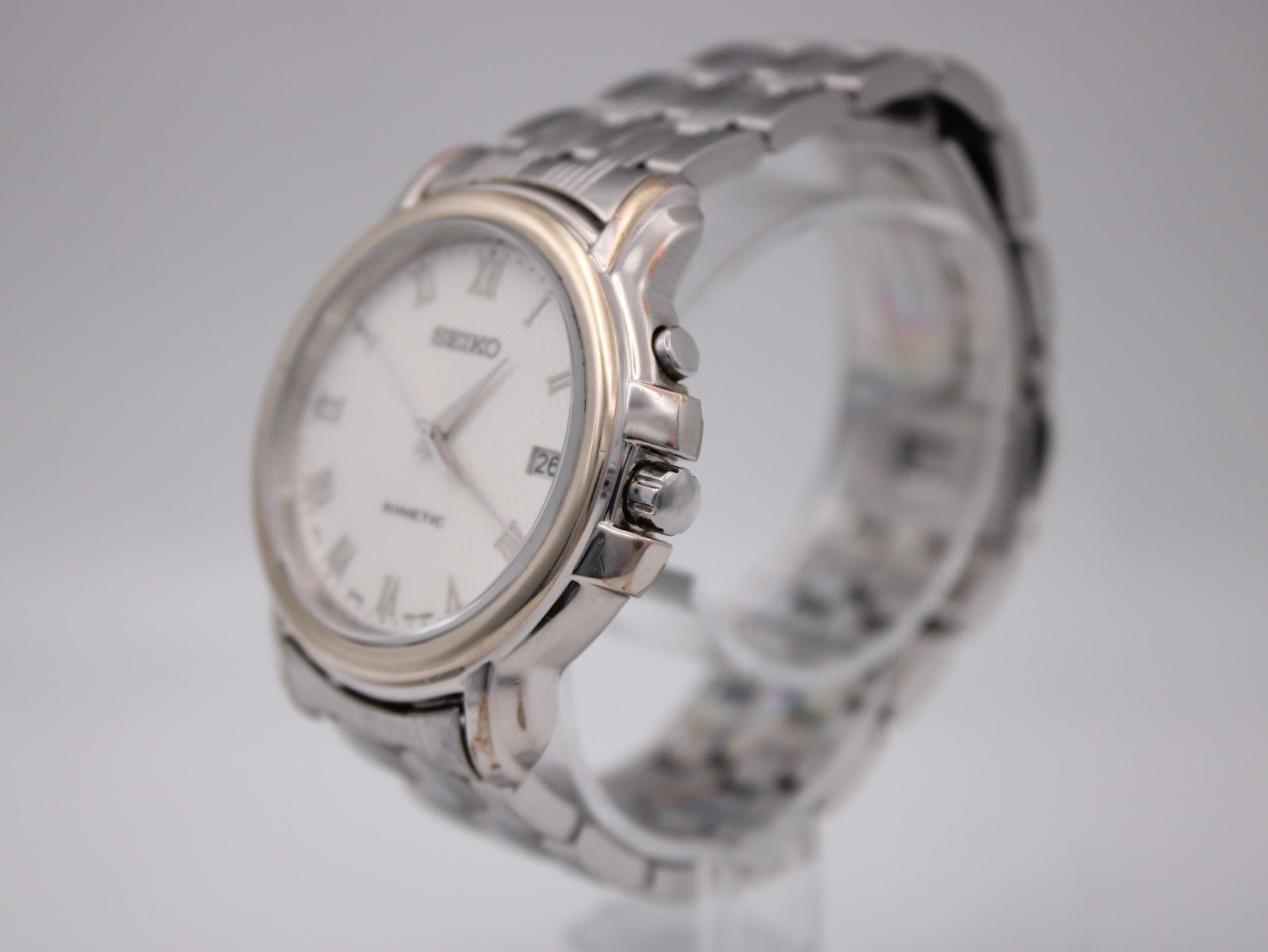 Angled side view of the Seiko watch, highlighting the silver-tone case, gold bezel, and integrated bracelet.