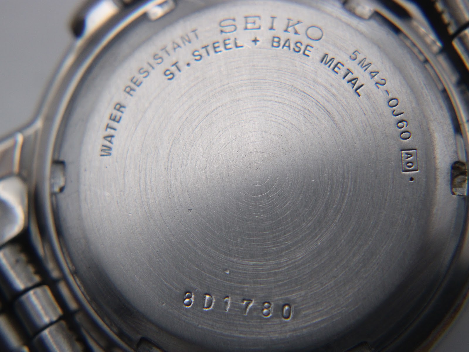 Close-up of the Seiko case back, showing "Water Resistant", "St. Steel + Base Metal", "5M42-0J60", and serial "8D1780".