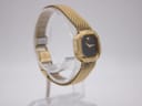 Close-up view of the gold-toned folding clasp and safety chain on the mesh bracelet.