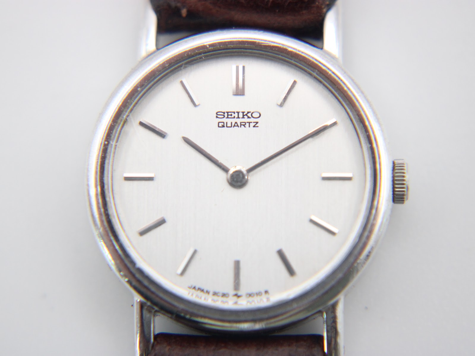 Macro shot revealing the brushed silver dial and applied baton hour markers.