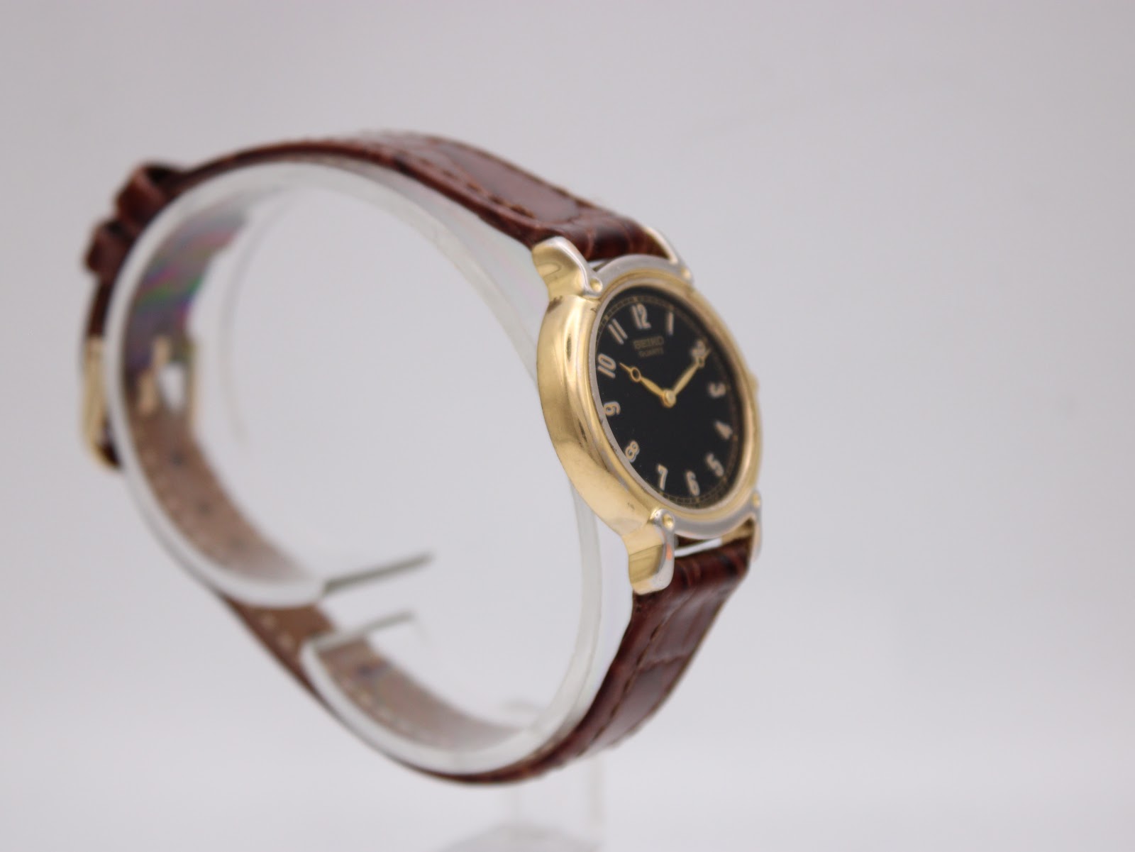 Close-up of the watch's case back, showing Seiko branding, base metal, stainless steel back, model, and serial number.