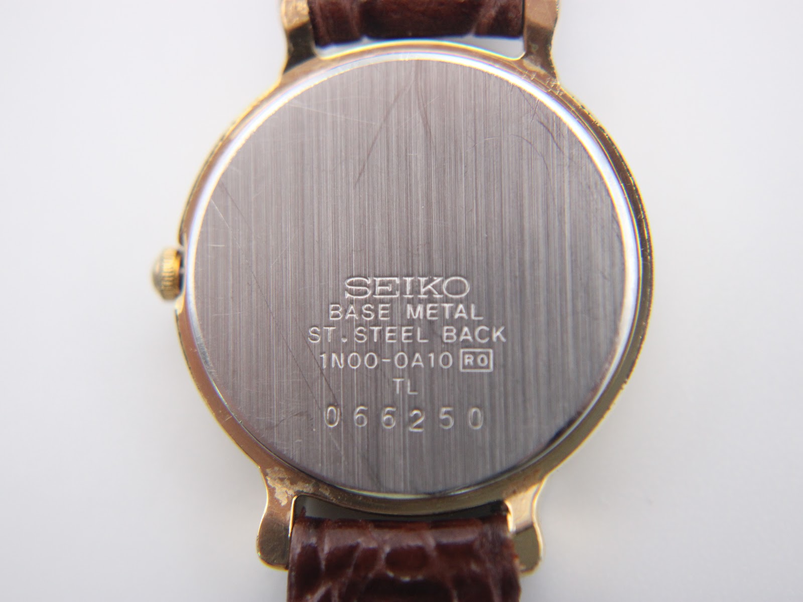 Detailed close-up of the black dial with gilt Arabic numerals and gold-tone hands.
