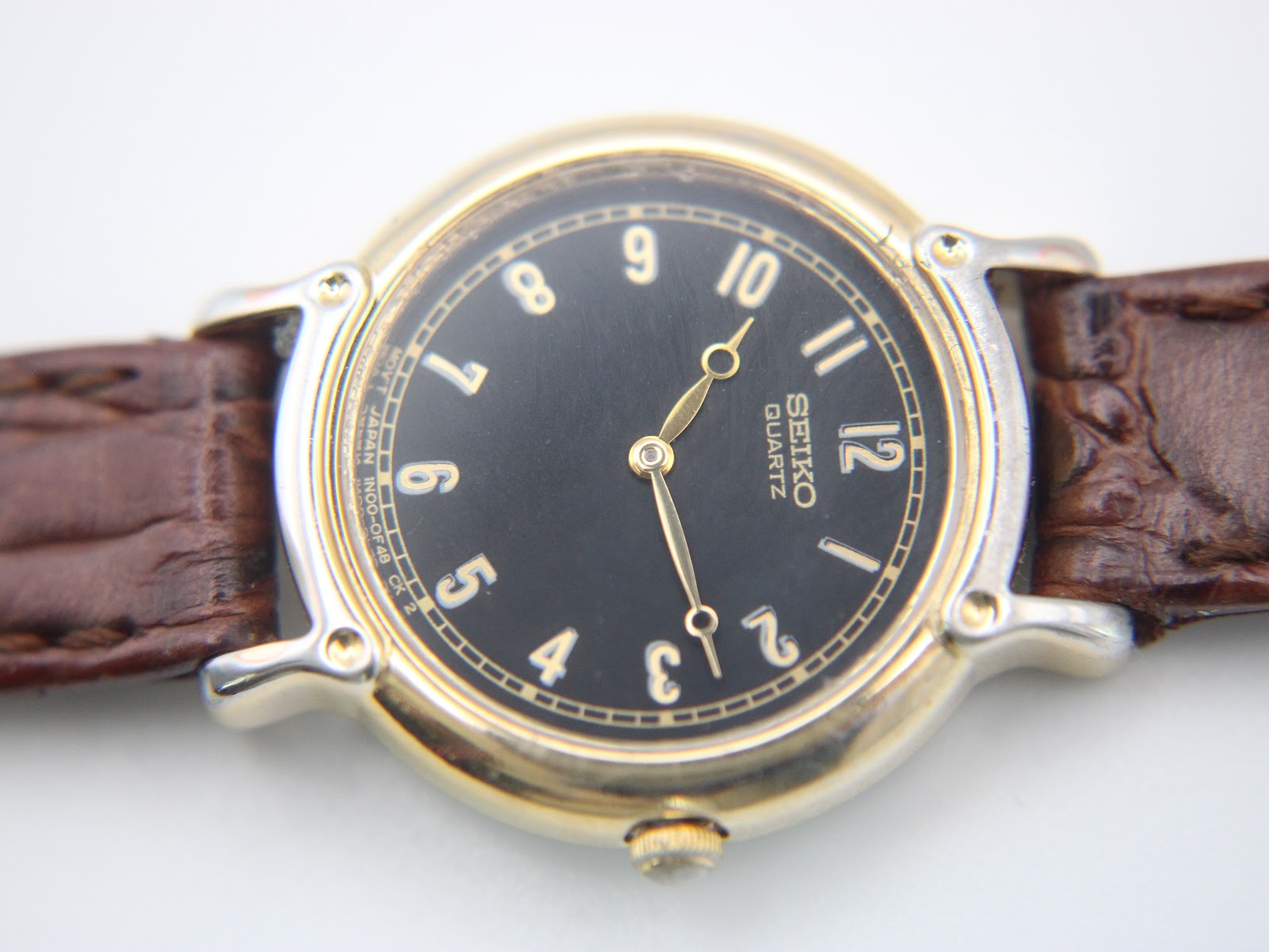Full view of the watch on its dark brown crocodile-pattern leather strap with gold-tone buckle.