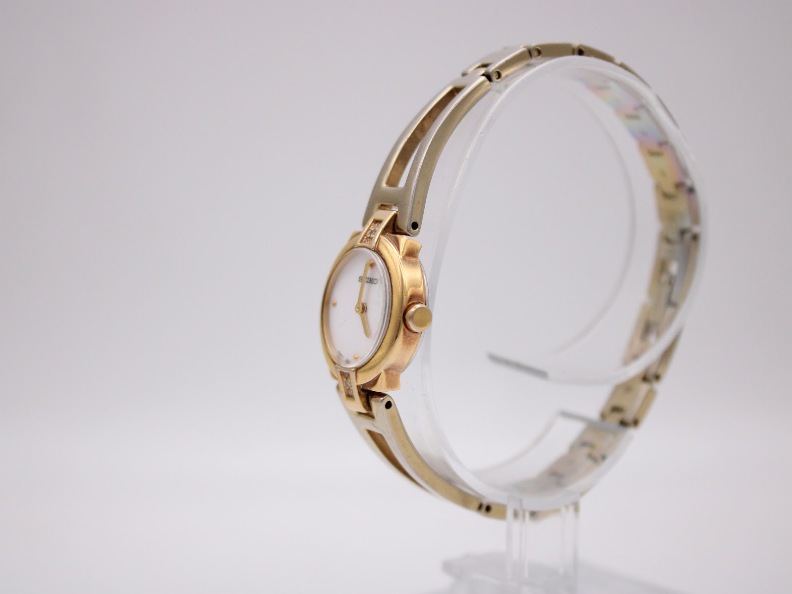 Angled side view of the Seiko watch on a display stand, highlighting the gold-tone case and bracelet design.