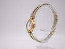 Angled side view of the Seiko watch on a display stand, highlighting the gold-tone case and bracelet design.