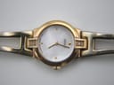 Close-up of the watch dial, clearly showing the mother of pearl finish, gold-tone dot indices, hands, and the small clear stone accents on the lugs.