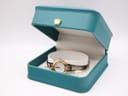 The Seiko watch displayed open in a teal-coloured jewellery box, showing the dial and bracelet on a white inner cushion.